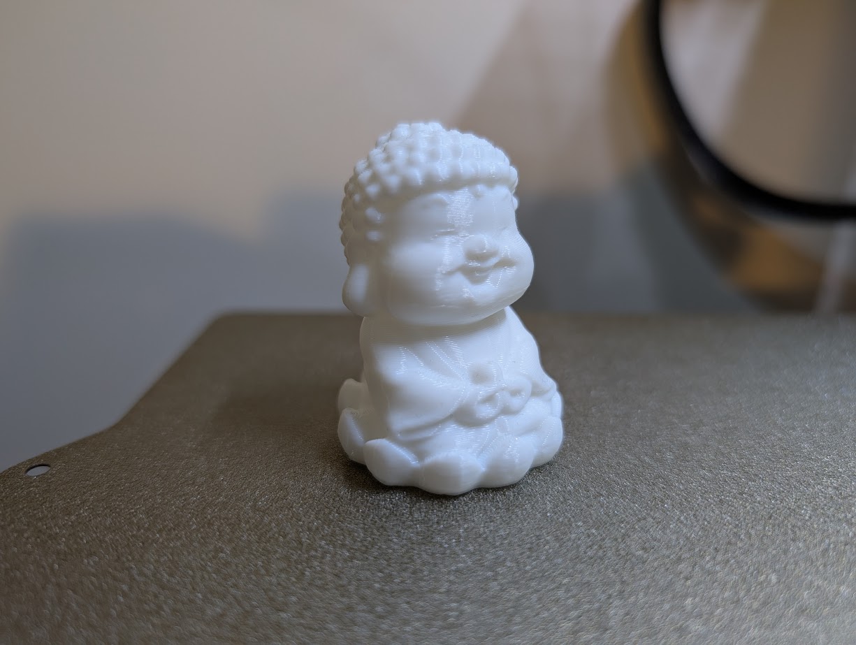 White 3D printed Buddha figure on a printer bed